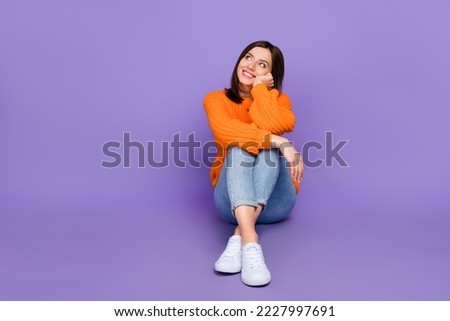 Full body photo of stunning young girl sit look dreamy empty space dressed stylish orange knitted look isolated on purple color background