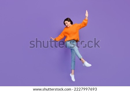 Full body photo of stunning young girl dancing enjoy party weekend dressed stylish orange knitted look isolated on purple color background Royalty-Free Stock Photo #2227997693