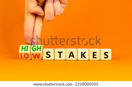 High or low stakes symbol. Concept words High stakes and Low stakes on wooden cubes. Businessman hand. Beautiful orange table orange background. Business high or low stakes concept. Copy space. Royalty-Free Stock Photo #2228000505