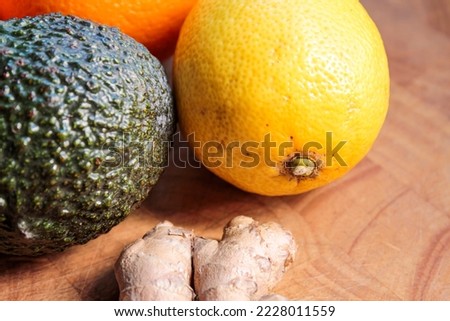 A ripe avocado with an orange and ginger on a wooden cutting board in the kitchen. A still life for a meal calendar or kitchen picture.