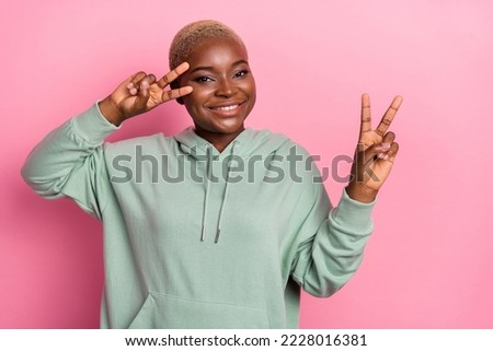 Photo of young female with short fair hair showing v sign make dancing moves isolated on pink color background