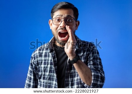 One college student holding hand near mouth and shouting, isolated on blue background.