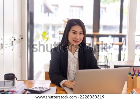 Businesswoman using laptop near gadgets on table