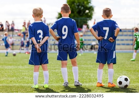 Football soccer match for children. Kids waiting on a pitch sideline. Sporty boys in soccer jersey clothes and cleats Royalty-Free Stock Photo #2228032495
