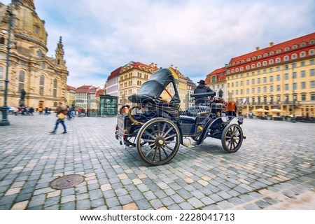 Old carriage on blurred background of Frauenkirche at Neumarkt square in downtown of Dresden.  Location: Dresden, state of Saxony, Germany, Europe