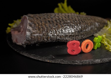 Fish percent discount on Black Friday, cheaper item placed on black board and background. Cleaned cut fish.