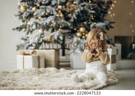 Cute baby girl sitting by the christmas tree