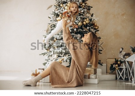 Mother with her baby daughter sitting under the christmas tree