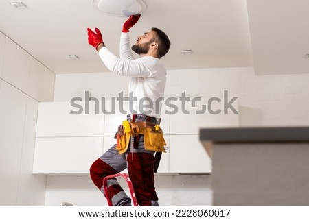 Electrician worker installation electric lamps light inside apartment. Construction decoration concept. Royalty-Free Stock Photo #2228060017