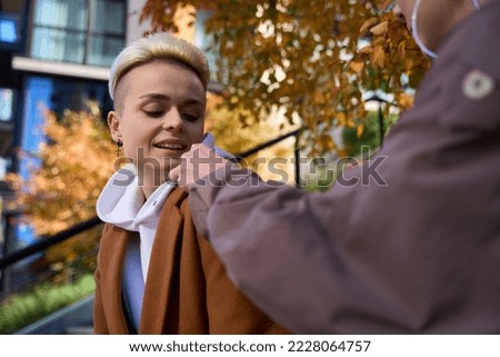 Blonde with a friend are sitting in autumn city park
