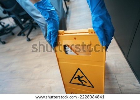 Worker puts up a warning sign about a wet field Royalty-Free Stock Photo #2228064841