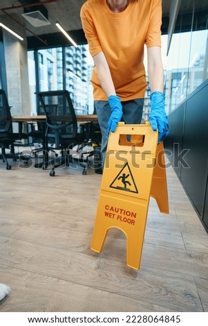 Janitor putting wet floor warning sign in office area