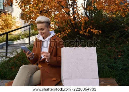 Young woman is resting on bench, she is in correspondence phone