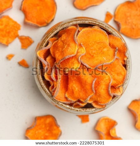 Healthy organic sweet potato chips in a bowl on a stone background. Root vegetables. Vegetarian and vegan appetizer. Diet. A useful snack. Selective focus, top view, square picture