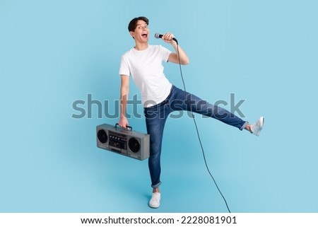 Photo of nice glad guy hold boom box sing mic wear t-shirt isolated blue color background.