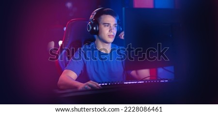 Happy Young caucasian man pro gamer streamer play in online video game, neon color soft focus. Concept banner esport tournament.