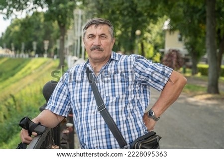 Portrait of a very old man 70 years old with a bag. Grandpa is resting in the summer outdoors. Portrait: aged, elderly, senior. Close-up of an old man standing alone. Royalty-Free Stock Photo #2228095363