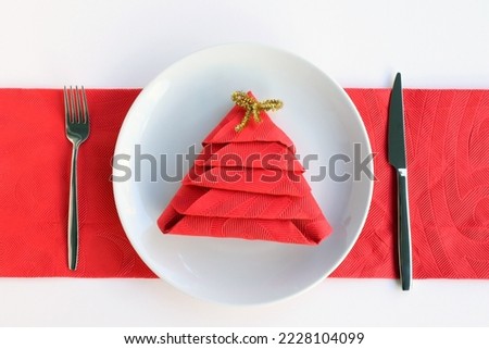 Red napkin folded in pine tree shape in plate with cutlery set.Christmas or New Year Concept