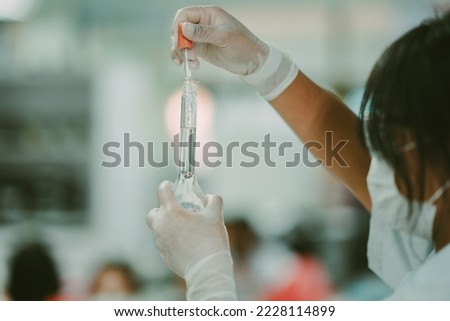 Chemistry laboratory education concept, chemical solution test for student in classroom, close up hand holding dropper transfer chemical solution to volumetric flask, safty gloves on hand of chemist