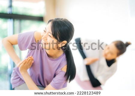 Asian woman taking a lesson in yoga class Royalty-Free Stock Photo #2228123489