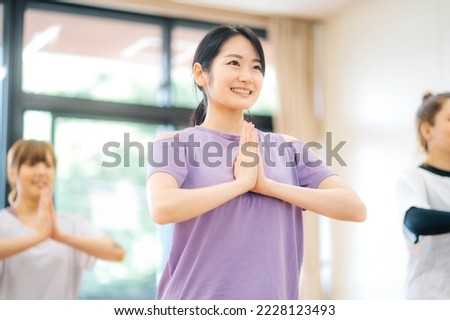 Asian woman taking a lesson in yoga class Royalty-Free Stock Photo #2228123493