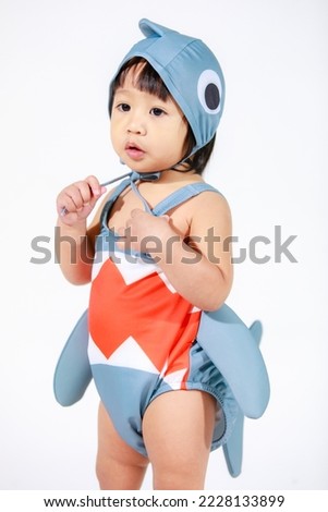 Studio shot of little beautiful kindergarten Asian baby girl daughter model in cute gray shark costume swimsuit outfit standing on white background