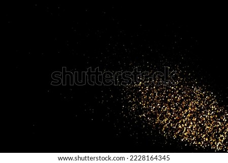 Gold glitter powder sparkling on black background.Close-up gold glitter powder,abstac dust golden light has bokeh,golden glitter texture christmas 