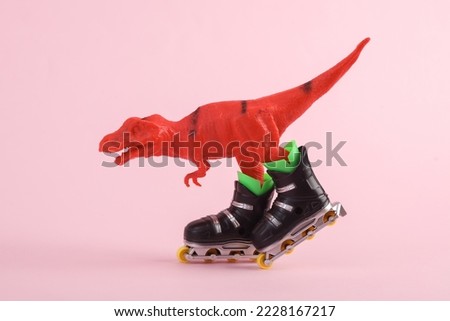 Toy red dinosaur tyrannosaurus rex with roller skates on pink background. Minimalism creative layout