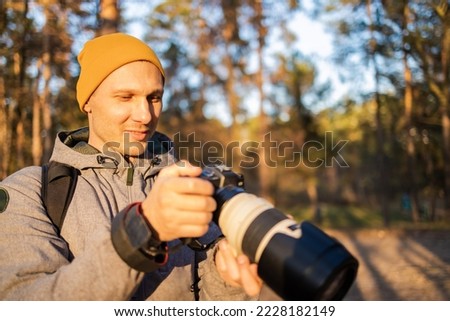 Young photographer taking photo in the forest. photographer with big professional camera.