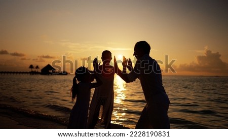 Family People On Beach. Sunset Silhouette High five