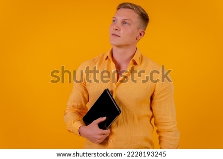 Caucasian blond businessman man on a yellow background, portrait with a tablet