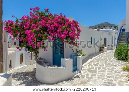 Traditional Cycladitic alley with a narrow street, whitewashed houses and a blooming bougainvillea in lefkes village, Paros island, Greece. Royalty-Free Stock Photo #2228200713