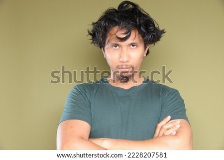 Asian male in messy hair with stress emotion over green background. Royalty-Free Stock Photo #2228207581