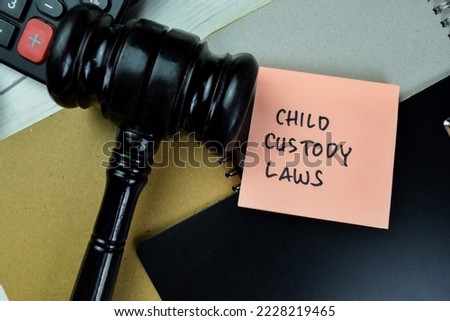 Concept of Child Custody Laws write on sticky notes with gavel isolated on Wooden Table.