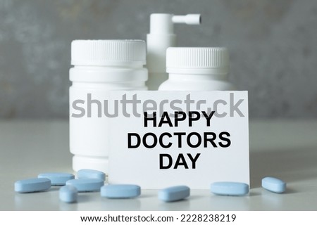 Happy Doctor's Day text on a card on the table next to the medicine in jars and scattered tablets