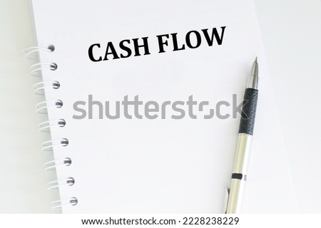 Cash Flow text on a notebook on a table next to a pen, a business concept