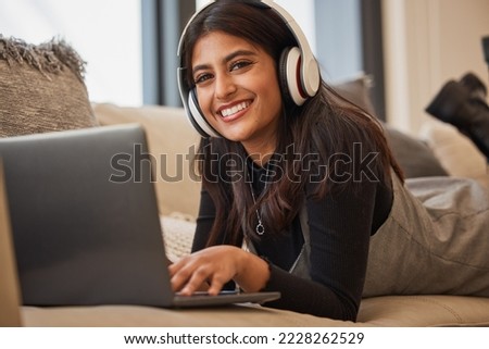 Headphone, woman and relax on laptop, happy and listening to music, podcast or watch a movie on the sofa in home. Portrait, young girl and happy with streaming subscription app, audio or social media