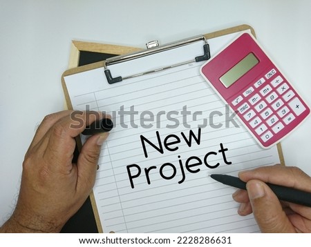 Hand holding pen, Text written New Project at paper on clipboard and calculator on white background 