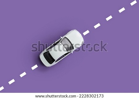 
abstract white car rides on the road with markings. purple or lilac background. top view. copy space Royalty-Free Stock Photo #2228302173
