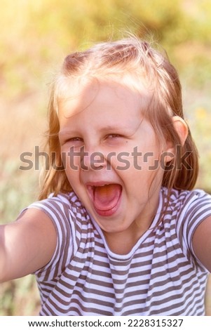 Smiling little girl in the park. Copy space. Happy child looking at the camera. Portrait of a laughing kid outside. Take a selfie