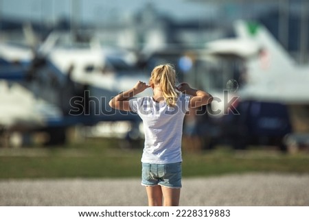 Young, blond girl covering her ears on loud airport