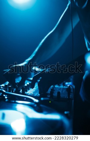 Club dj mixing music set on party in bright blue lights. Silhouette of disc jockey on stage Royalty-Free Stock Photo #2228320279