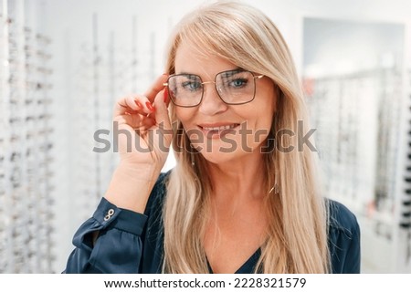 Looking at the camera. Woman in store trying new glasses.