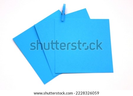 Turquoise, blue colored note papers shot on White while blue clothespin hold them.