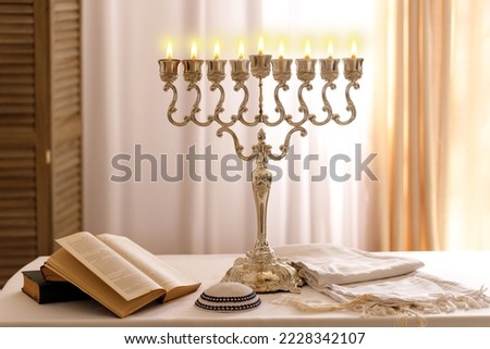 Jewish religious holiday Hanukkah with holiday Hanukkah (traditional candelabra),  tallit and Religious books (Tanakh) on table