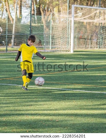 Football player in yellow uniform shooting the ball during a match