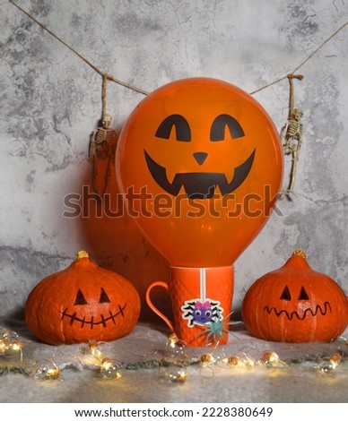 two Jack-o'-lantern heads in garlands. orange mug. decorative skeletons in the background