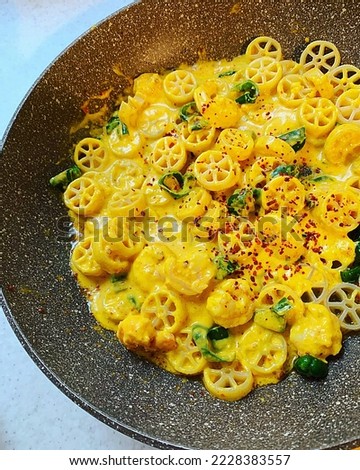 pasta dish in a pan, pasta circles, creamy pumpkin sauce, shrimps, green pepper and paprika powder, creamy pasta with sauce Royalty-Free Stock Photo #2228383557