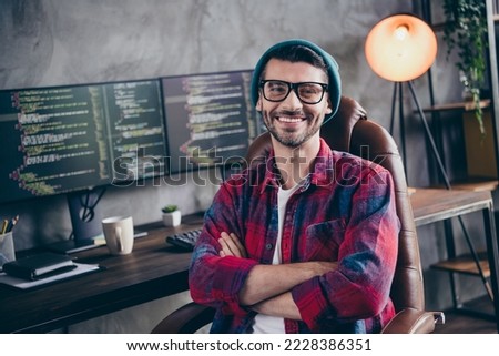 Photo of confident cheerful programmer wear spectacles arms folded smiling indoors workplace workshop home