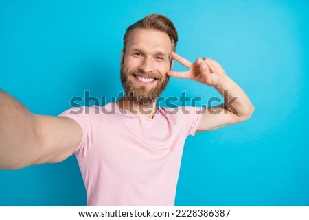 Photo portrait of nice young guy front camera streaming v-sign gesture dressed stylish pink outfit isolated on aquamarine color background